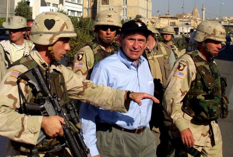 Deputy Secretary Wolfowitz is escorted by Gen. Petraeus as they walk through the streets of Mosul, Iraq.